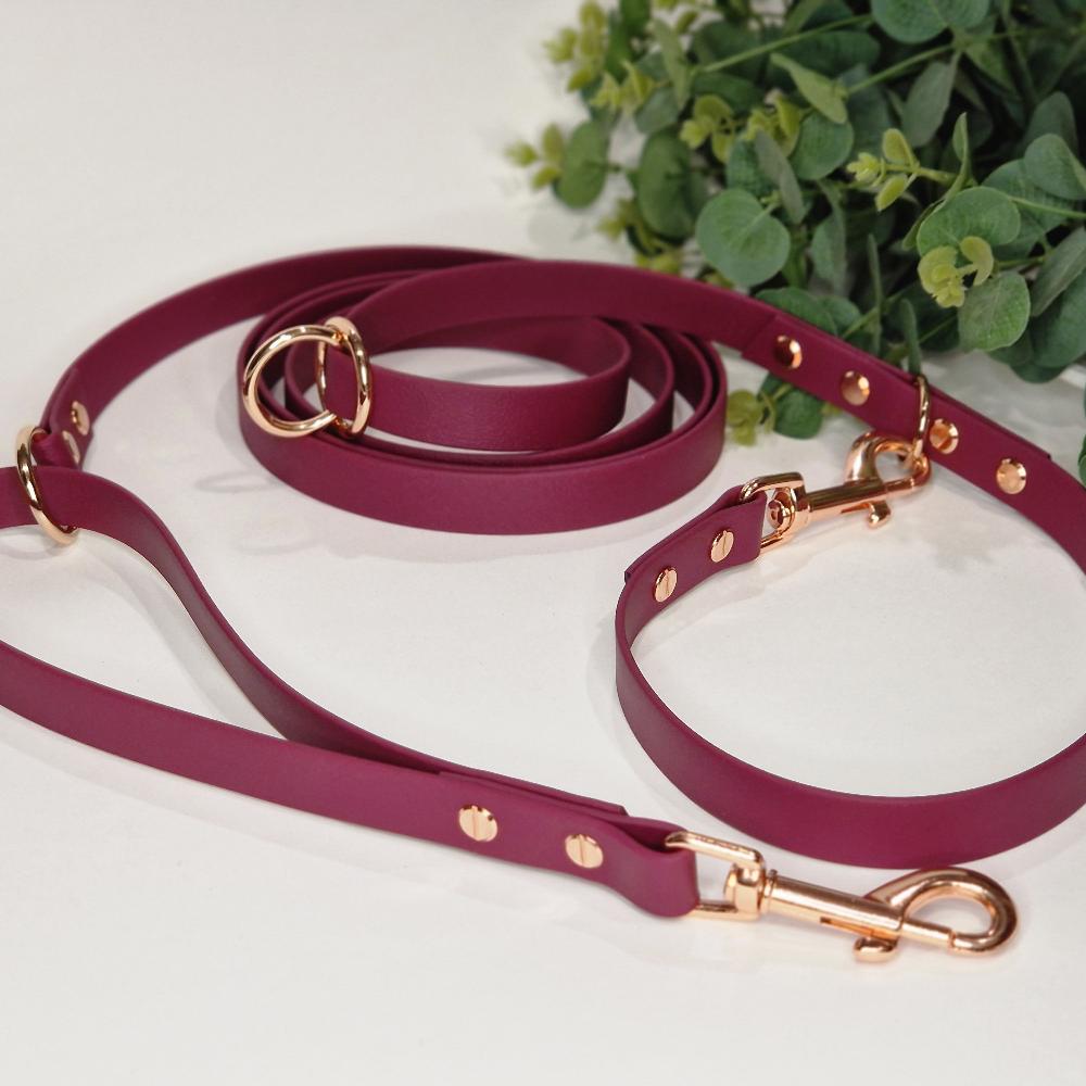 Wine-Colored Biothane Multifunctional Dog Leash with Copper Carabiners, thoughtfully arranged on a background of lush greenery for decoration.